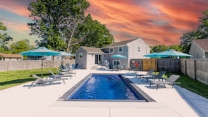 A backyard with a swimming pool, lounge chairs, and umbrellas. - Modern Renovated Retreat w/ Pool in North Cape May (Lower Township)