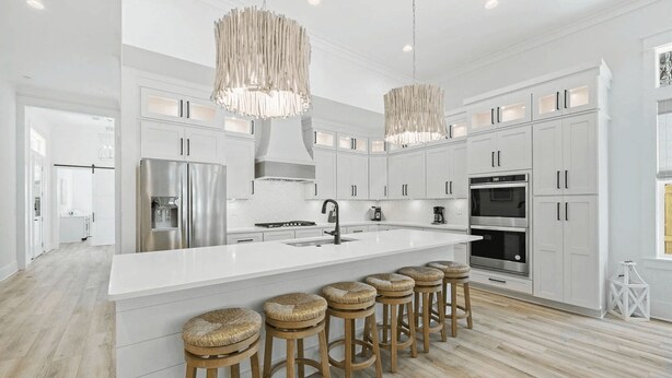 A modern kitchen with white cabinetry, stainless steel appliances, and a central island with bar stools. - Sleeps 34! 2 Homes, Private Pools, Firepit, Golf Cart, Walk to Beach Seagrove San Juan by Avantstay (Santa Rosa Beach)