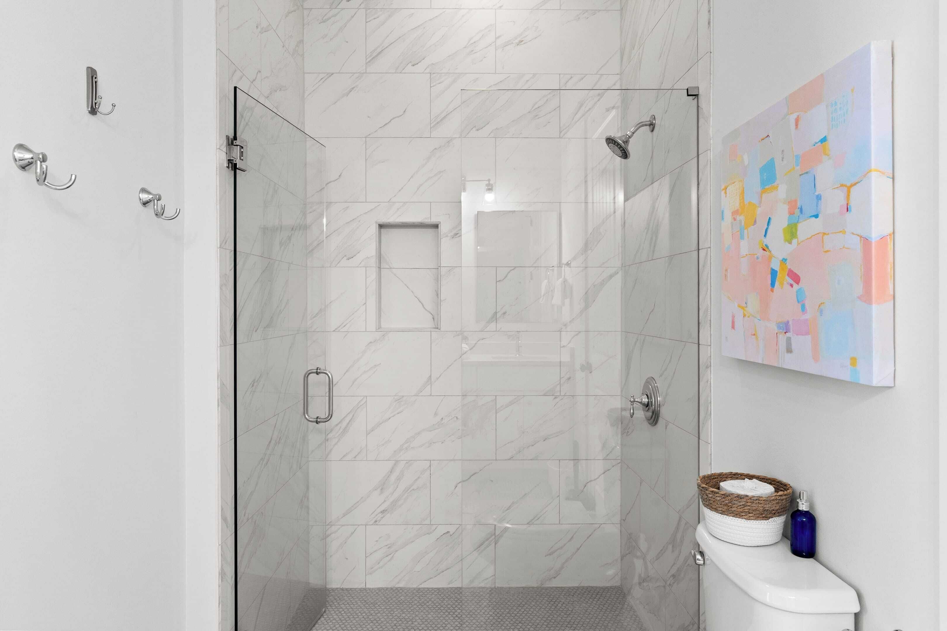 A modern bathroom with a glass shower enclosure, a toilet, and a wall-mounted sink.