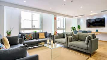 Una sala de estar moderna con sofás grises, una mesa de centro de vidrio y ventanas amplias.