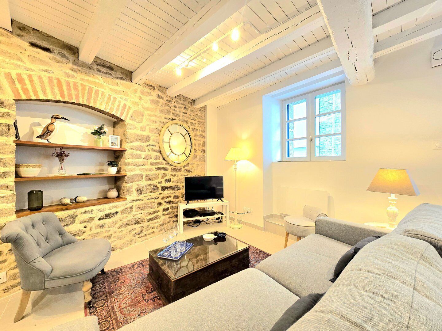A cozy living room with a stone wall, a flat-screen TV, a sofa, and a coffee table.