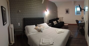 Habitación de hotel con una cama grande, un escritorio, una silla y un radiador.