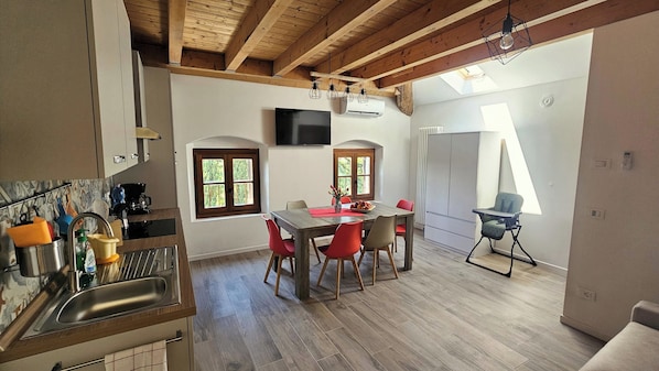 Una cocina moderna con comedor, vigas de madera, televisor y vistas al exterior.