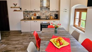 A modern kitchen with white cabinets, a wooden ceiling, and a dining area with a table set for two. - Exclusive Family Vacation: High-Quality, Stylish Apartment in Milan, 10 Minutes from Gardaland (Venetien)