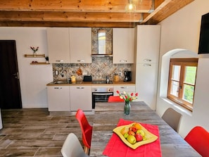 Una cocina moderna con armarios blancos, techo de madera y comedor con una mesa para dos.