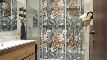 Ein Badezimmer mit einem Holzkosmetikschrank, einer Duschkabine mit Blattmuster und einer Toilette.