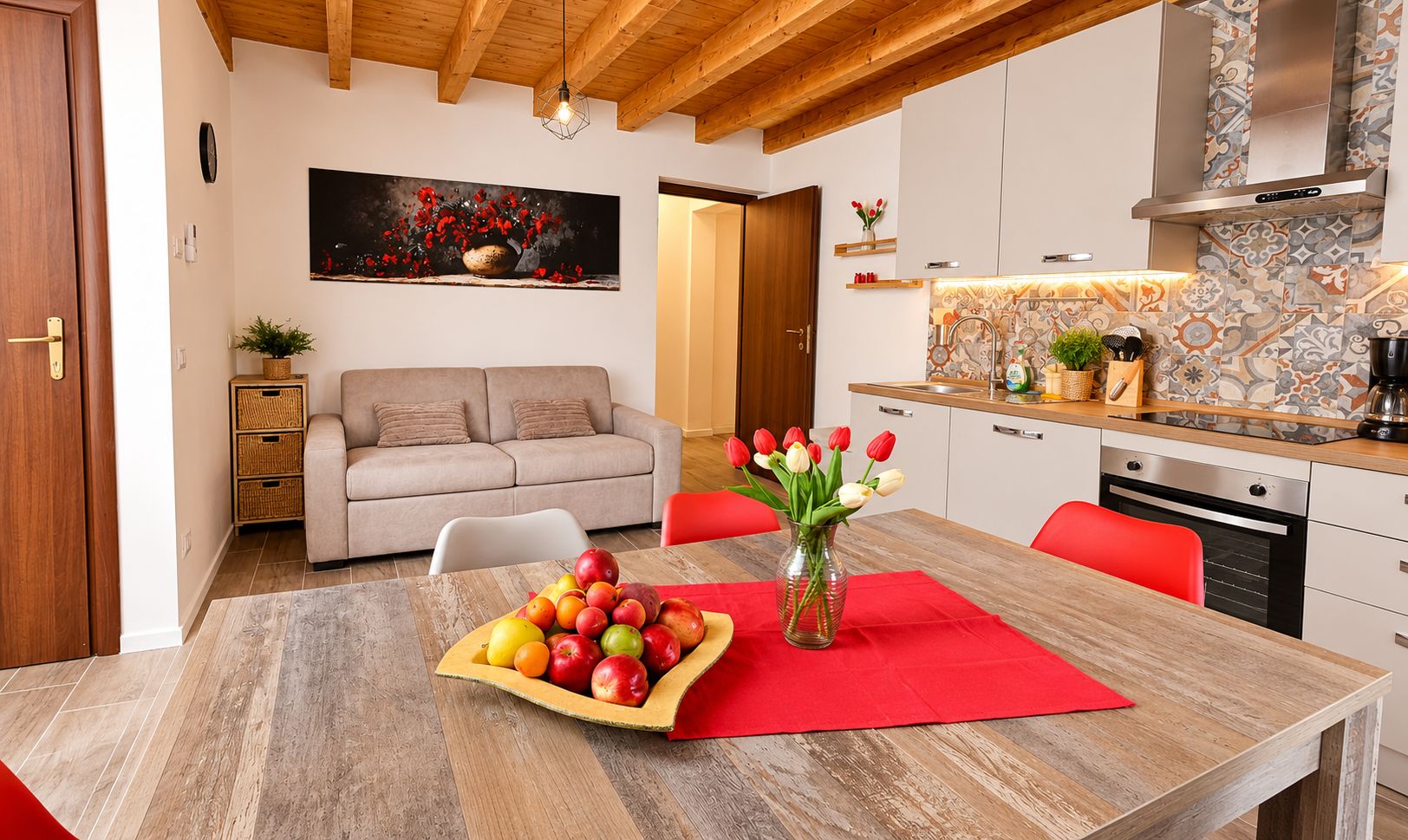 A modern kitchen with white cabinets, a wooden countertop, and a red vase with tulips on the dining table.