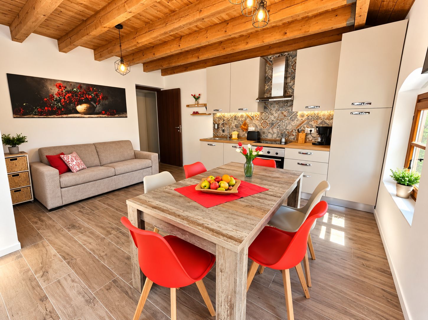 A modern kitchen with white cabinets, a wooden dining table, and red chairs.