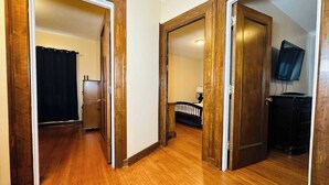 Un pasillo con piso de madera y puertas que dan a diferentes habitaciones.