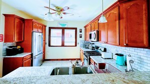Una cocina con armarios de madera, un refrigerador de acero inoxidable, un microondas y una estufa a gas.