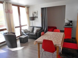 A modern living room with a sofa, a dining table, and a coffee machine.