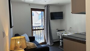 A compact living space with a sofa, a dining table, a TV mounted on the wall, and a window with a curtain. - 150m from ski slopes, 1st floor, view village, balcony, tv, ski locker, 20m², Montgenèvre (Montgenèvre)
