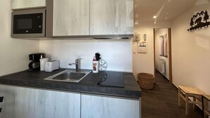 A compact kitchen with a microwave, toaster, and sink. - 150m from ski slopes, 1st floor, view village, balcony, tv, ski locker, 20m², Montgenèvre (Montgenèvre)