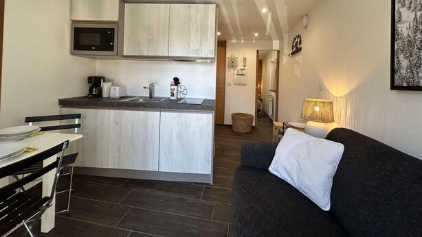 A compact living space with a kitchenette, a dining area, and a seating area with a sofa and a lamp. - 150m from ski slopes, 1st floor, view village, balcony, tv, ski locker, 20m², Montgenèvre (Montgenèvre)