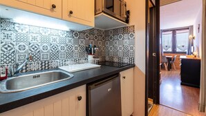 Une cuisine avec des carreaux décoratifs, un évier, un lave-vaisselle et un four à micro-ondes.