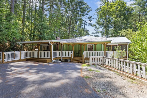 Une cabane dotée d’une véranda, d’un porche abrité et d’une allée gravillonnée.