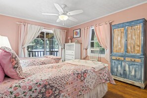 A bedroom with two beds, a ceiling fan, a dresser, and a window with curtains.