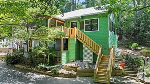 A two-story house with a wooden staircase and a green exterior.