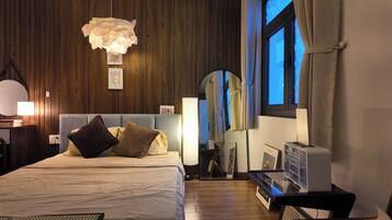 A hotel room with a bed, bedside lamp, bedside table, and a large mirror.
