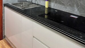 Een moderne keuken met een zwart aanrecht, een roestvrijstalen spoelbak en houten kastjes.