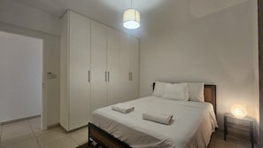 A bedroom with a bed, a wardrobe, a bedside table with a lamp, and a door. - 106 NIC - Stay Kallisto Old Town Apartment (Nicosia)