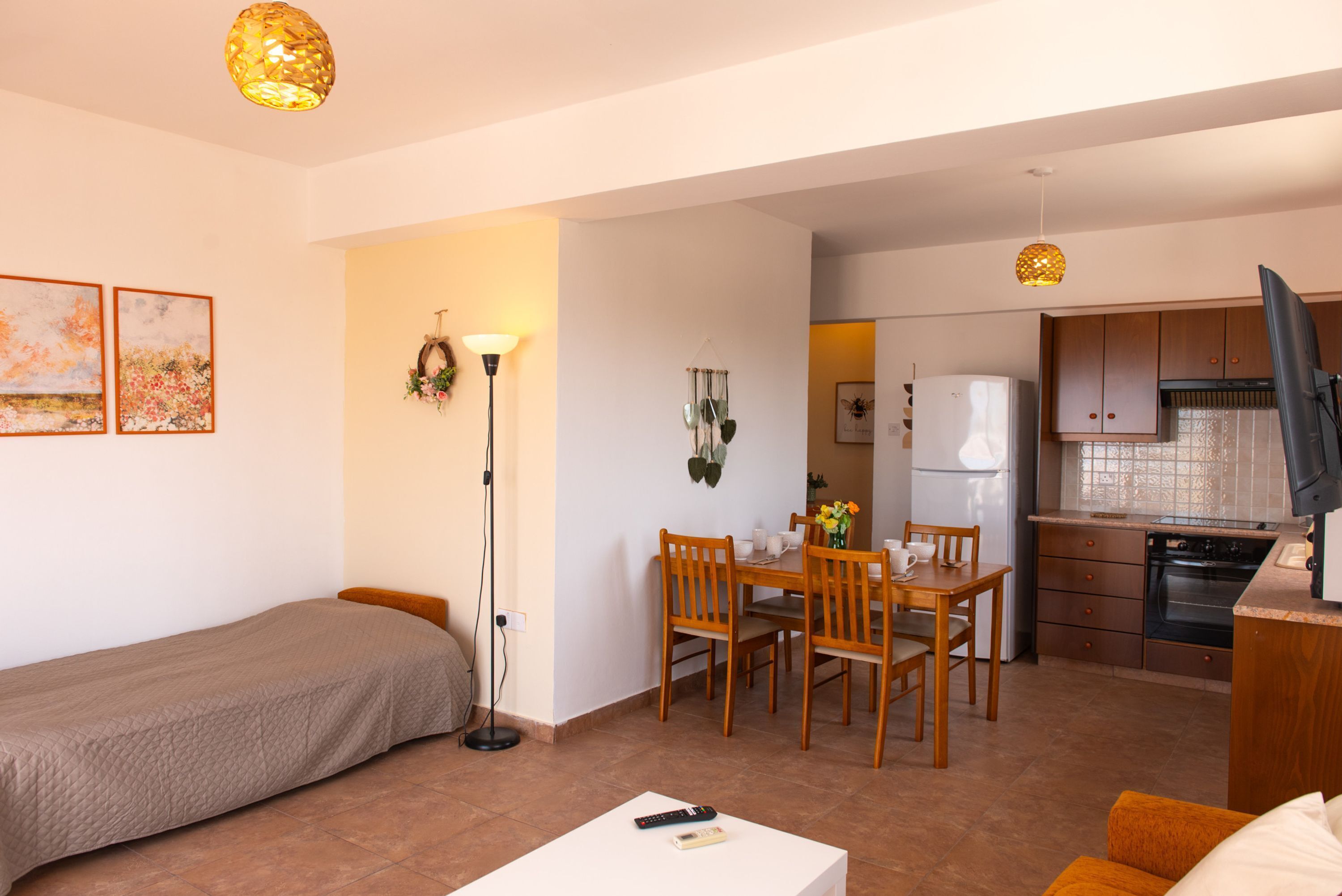 Un espace de vie compact comprenant un coin cuisine, un coin repas et un lit simple.