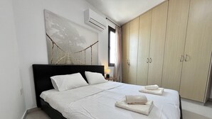 Ein modernes Schlafzimmer mit einem großen Bett, einem Kleiderschrank und einer Wand-Klimaanlage.