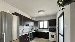 Eine moderne Küche mit Edelstahlgeräten, dunklen Schränken und einer integrierten Waschmaschine.