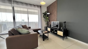 Ein modernes Wohnzimmer mit einer Couch, einem Fernseher und einer Pflanze.