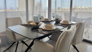 Ein moderner Essbereich mit Tisch für vier Personen, ausgestattet mit geometrischem Glas und neutralen Teller und Schüsseln.