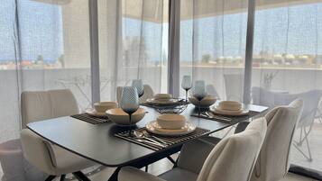 A modern dining area with a table set for four, featuring geometric glassware and neutral-toned plates and bowls.