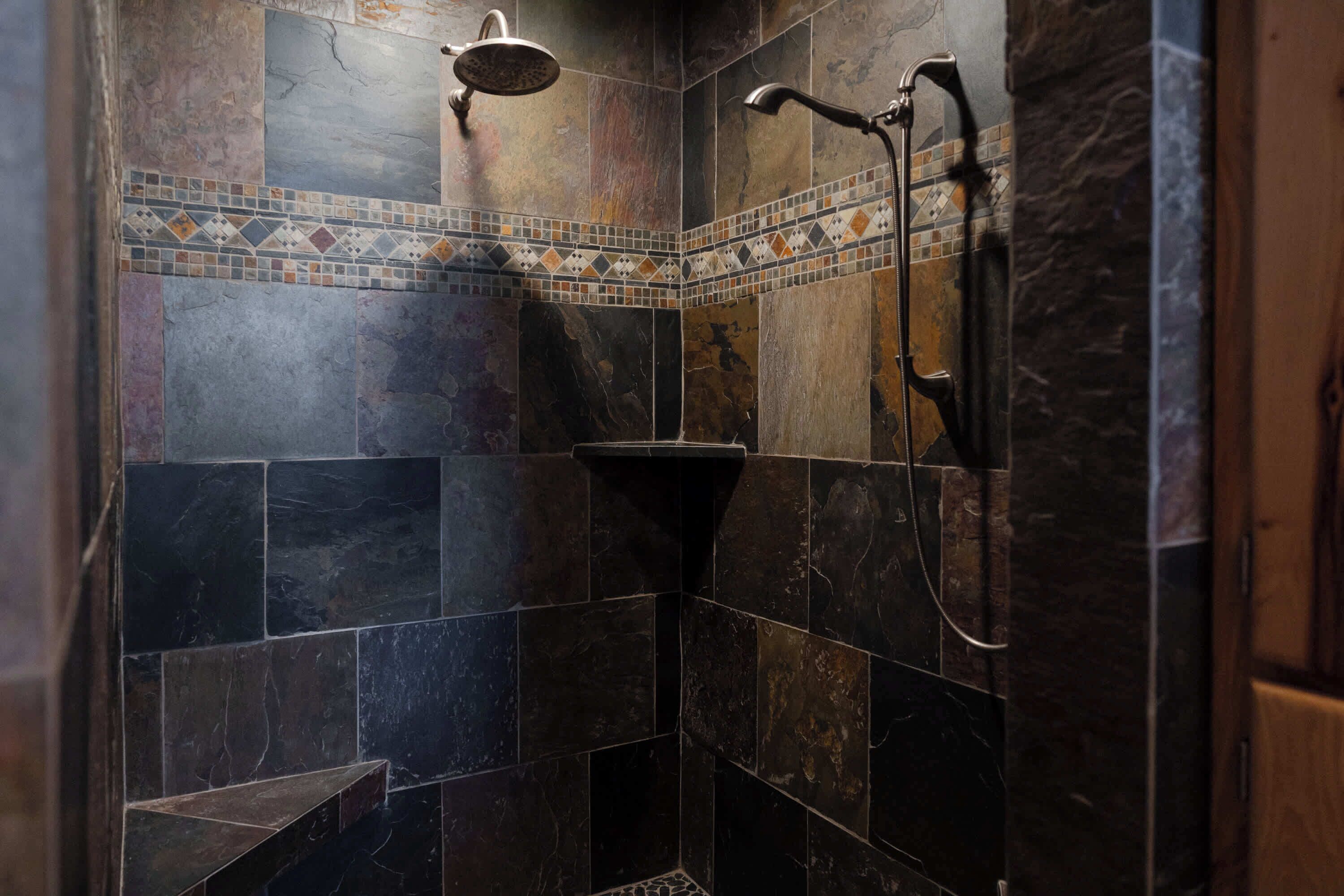A shower area with dark tiles and a mosaic border.