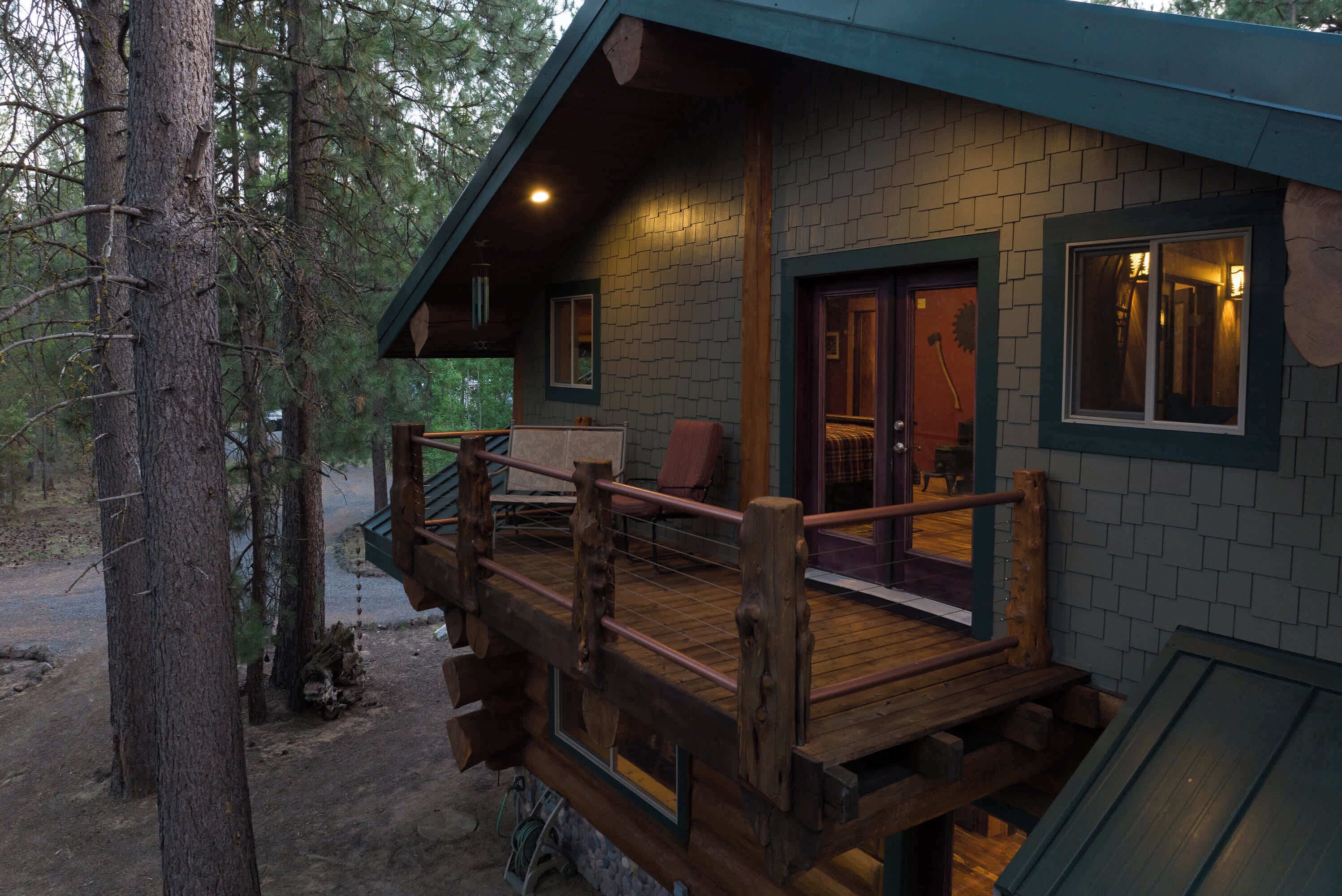 A cabin with a wooden deck, a covered porch, and a brick exterior.