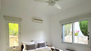 A bedroom with a bed, a nightstand, a window, and a ceiling fan. - 102 PAP - Stay Helios House (Mesa Chorio)