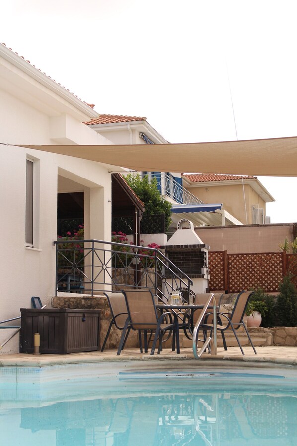 Une piscine avec des chaises longues et un espace patio couvert.