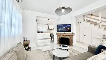 Una sala de estar moderna con un sofá, una mesa de centro, una chimenea y un televisor colocado sobre la chimenea.