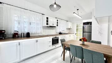 Una cocina moderna con armarios blancos, encimera de madera y una zona de comedor con mesa y sillas.