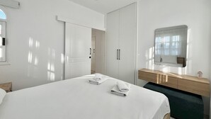 Een moderne hotelkamer met een groot bed, een houten kaptafel, een spiegel en een plafondventilator.