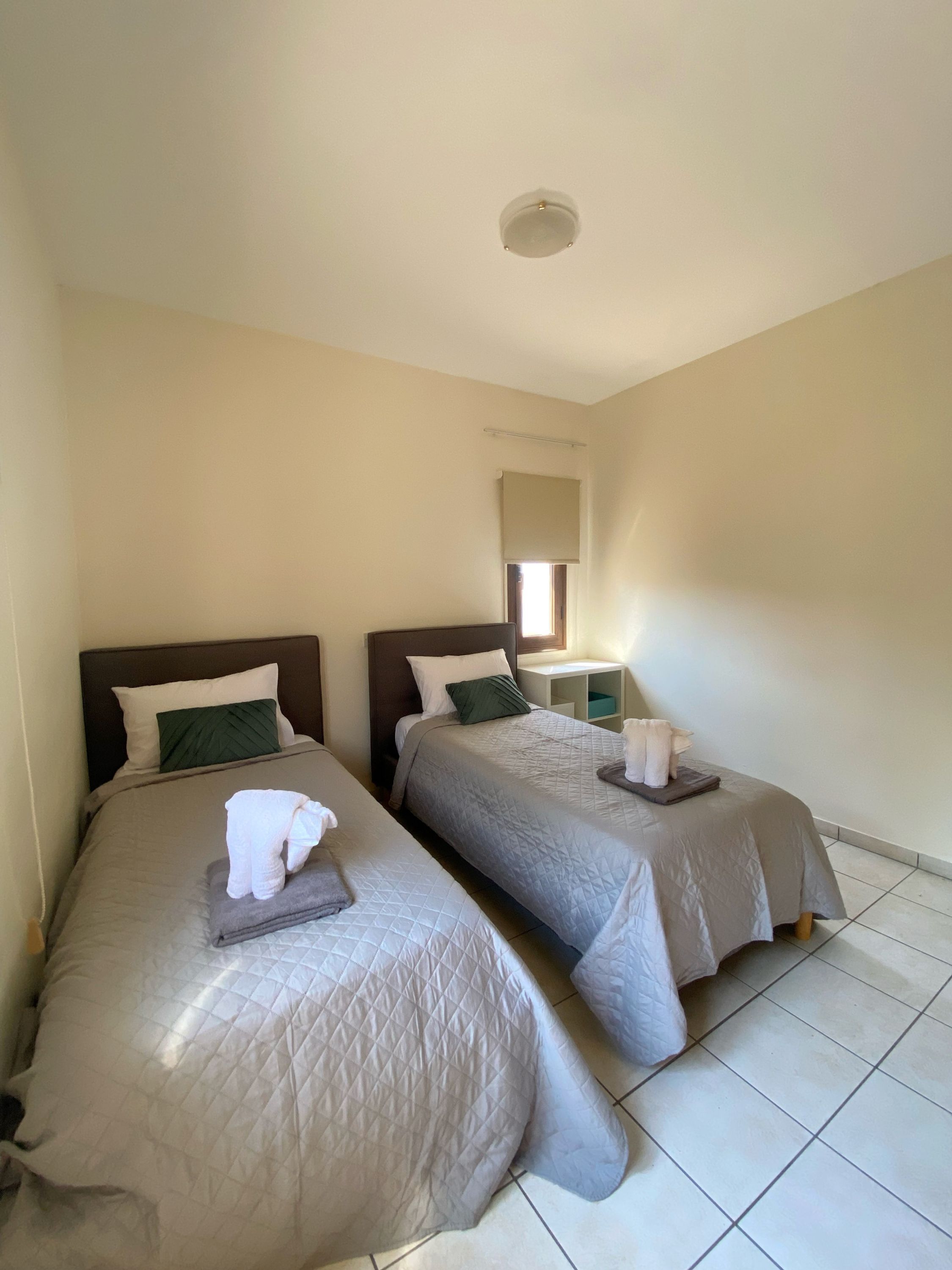 Une chambre d’hôtel avec deux lits, chacun étant équipé d’un oreiller et d’une serviette pliée.