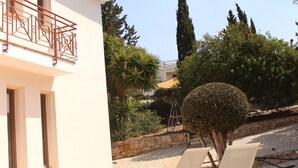 A building with a balcony, a well-maintained garden, and two lounge chairs. - 121 PEY - Stay Poseidon Villa (Pegeia)