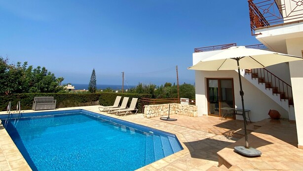 A swimming pool with lounge chairs, a staircase, and a view of the sea. - 121 PEY - Stay Poseidon Villa (Pegeia)