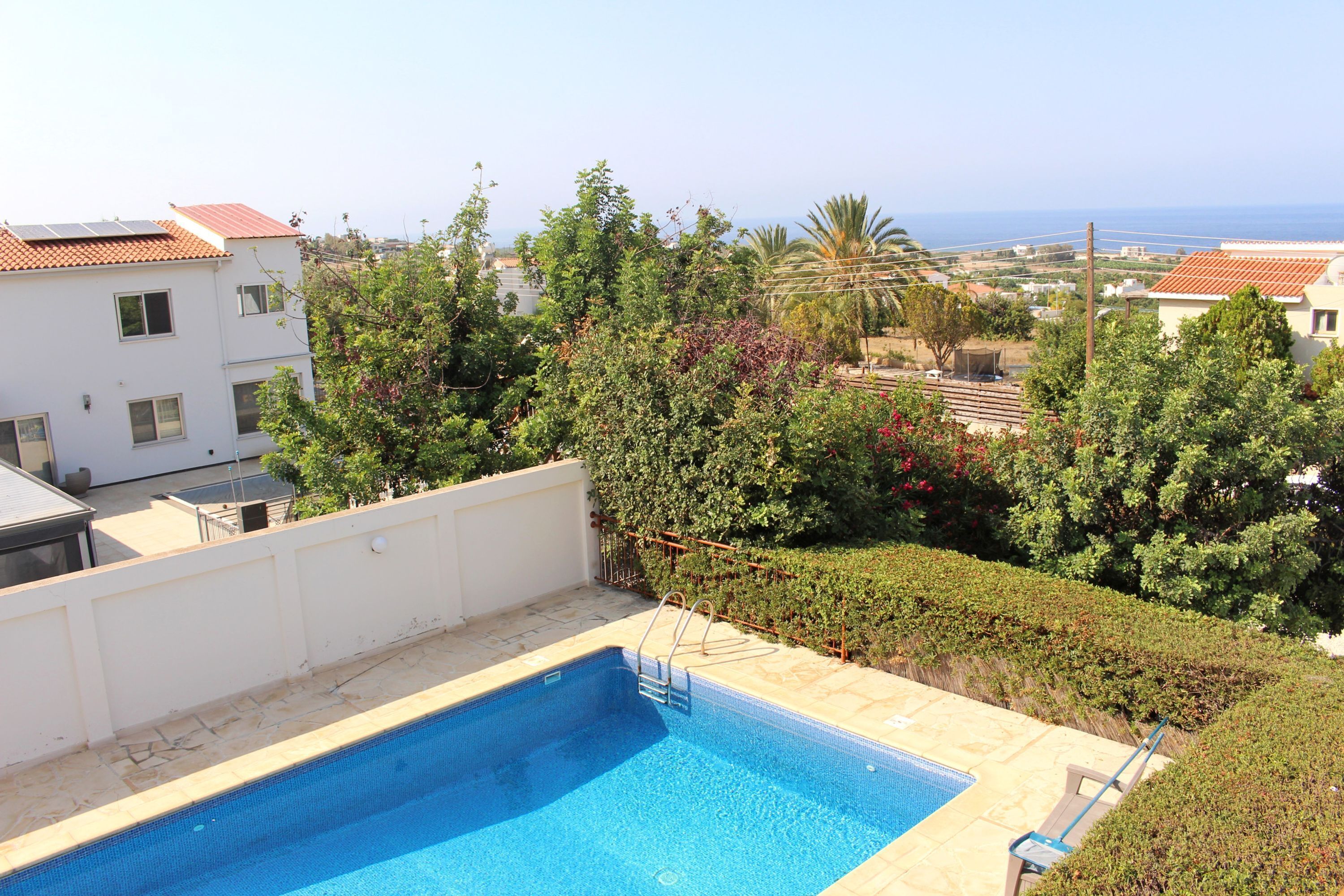 A rooftop swimming pool with a clear view of the sea and surrounding buildings.