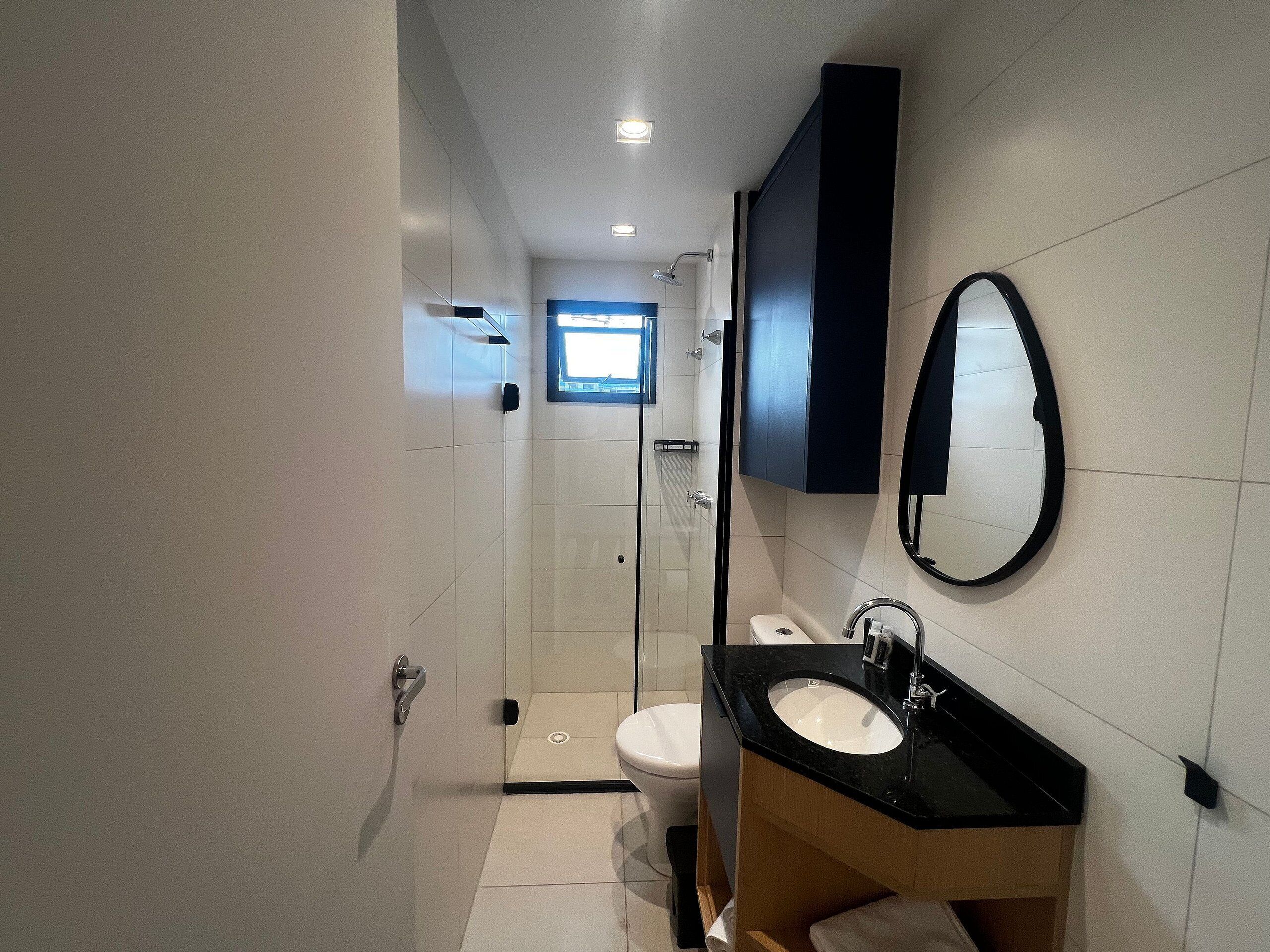 A modern bathroom with a black sink, white toilet, and a glass shower enclosure.