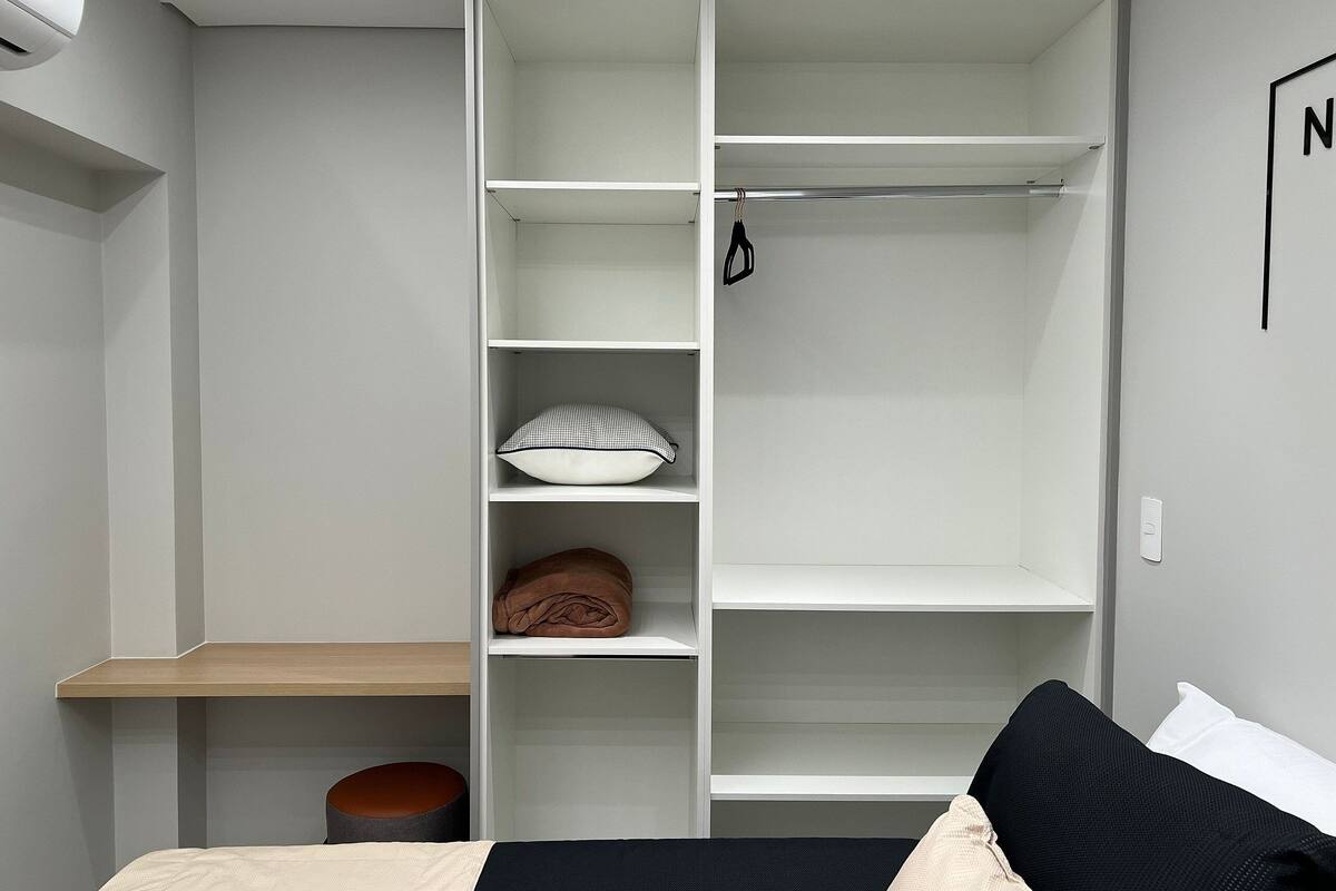 A bedroom with a bed, a wardrobe, and a small stool.