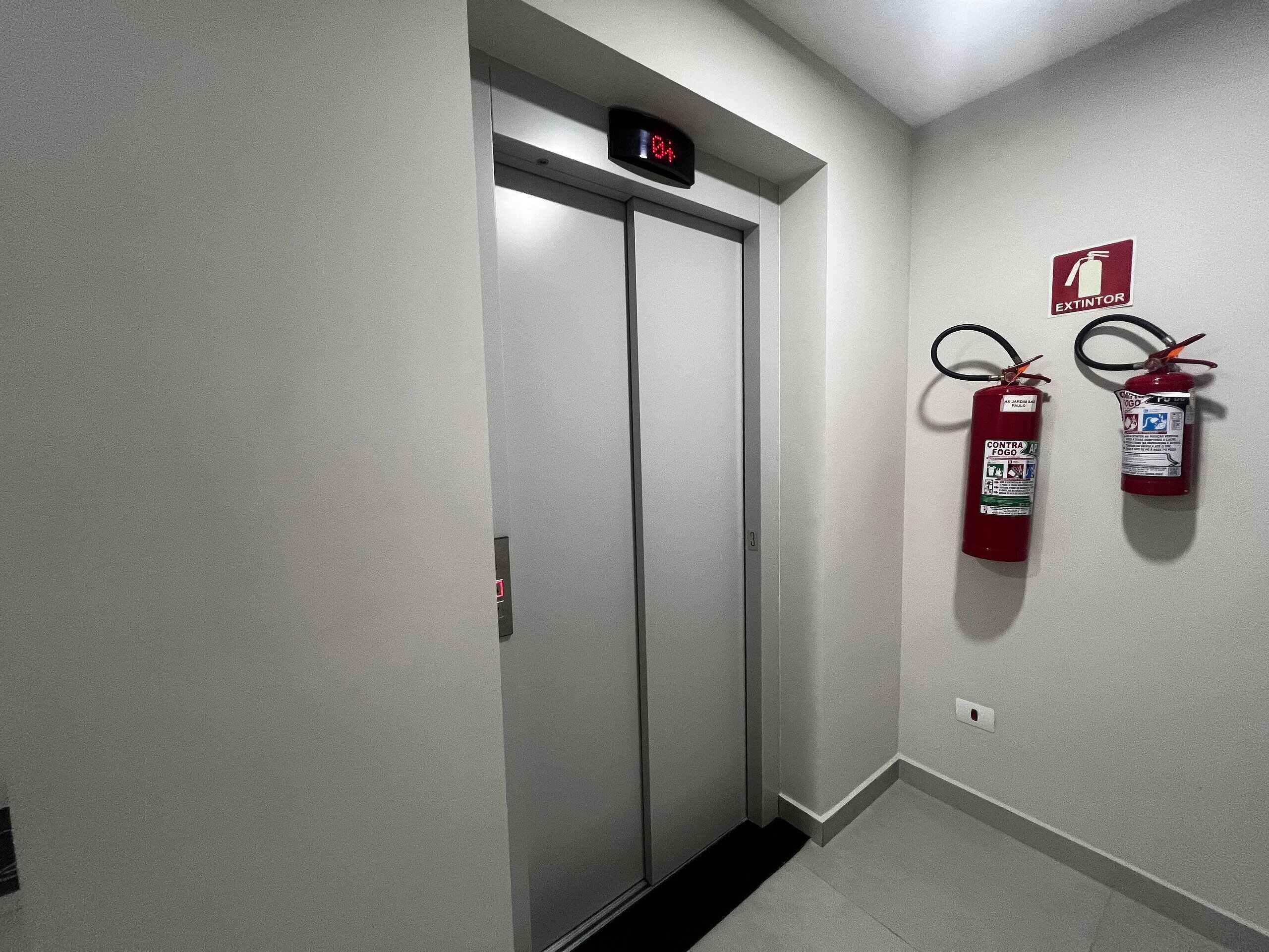Un couloir avec un extincteur et un ascenseur.