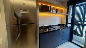 A modern kitchen with a stainless steel refrigerator, a microwave, and a gas stove. - Infinity Home Suítes Anhembi (Sao Paulo)
