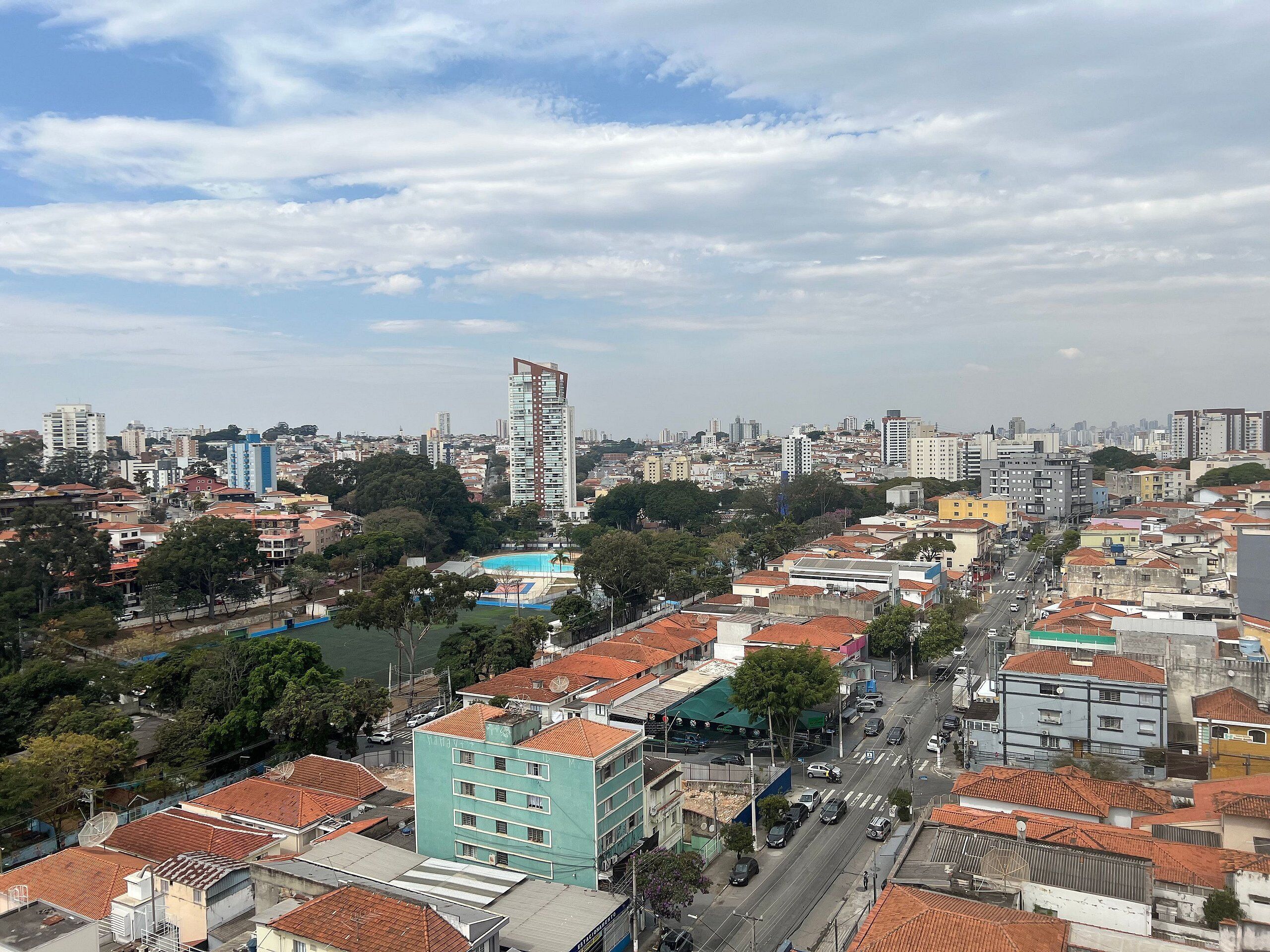 A cityscape with a prominent tall building, a mix of residential and commercial buildings, and a clear sky.