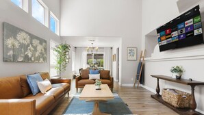 Een moderne woonkamer met een bank, salontafel en een aan de muur bevestigde televisie waarop diverse streamingdiensten worden getoond.