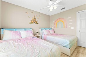 Camera da letto con due letti, una ventola a soffitto e decorazioni adesive al muro.