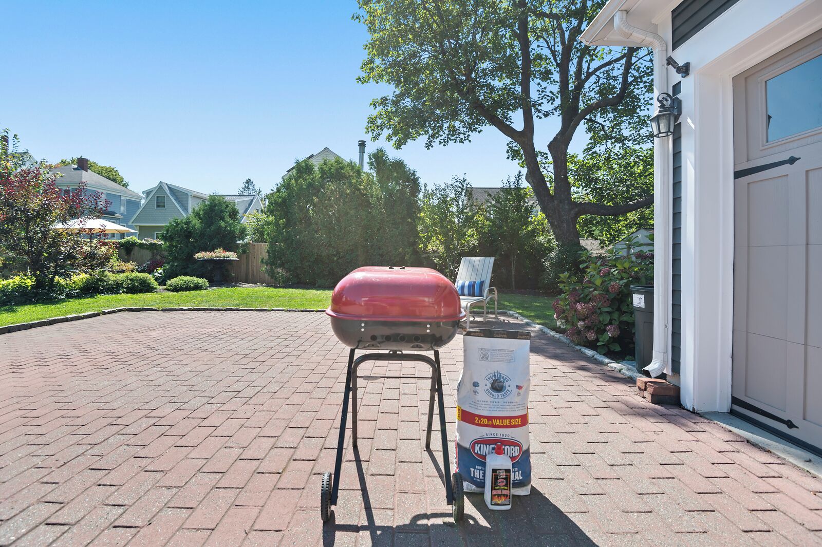 A barbecue grill and a bag of charcoal in a driveway.